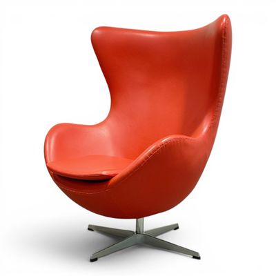 an orange leather egg chair with a metal base on a white background