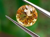 une image montrant un gros plan d'un diamant jaune tenu par une paire de pinces
