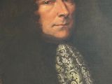portrait of a man in a black coat with a white and gold tie