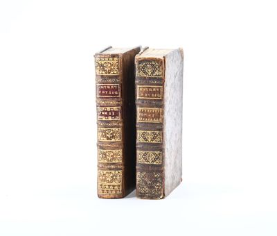 two old books are sitting side by side on a white surface