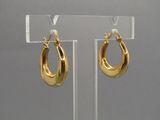une paire de boucles d'oreilles créoles dorées, présentées sur un support en acrylique transparent