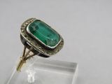 a close up of a ring with a green stone in it