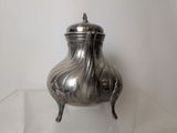 a silver tea pot on a clear glass table