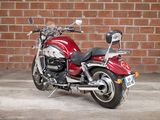 a red motorcycle parked in front of a brick wall