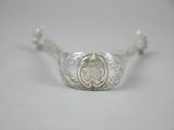 a close up of a silver spoon with a flower design on it