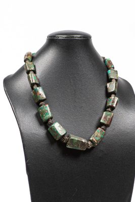 un collier composé de perles vertes et marron, posé sur un mannequin