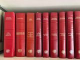 many red books lined up on a shelf in a library