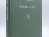 un vieux livre à la couverture verte posé sur une table blanche