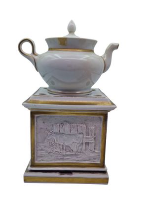 a white and gold teapot sitting on top of a box