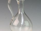 a clear glass pitcher with a handle on a table