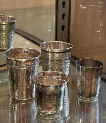 several silver cups are lined up on a table in front of a mirror