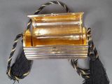 a gold purse with a black tassel on it