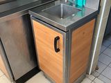 un évier dans un coin de la cuisine, à côté d'un réfrigérateur en acier inoxydable
