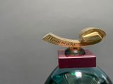 a bottle of perfume with a gold spoon on top of it