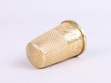 a gold thimble that is sitting on a white surface