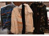 several coats are hanging on a rack in a room