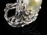 un gros plan d'une bague en perle et argent posée sur une surface noire
