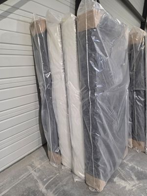 Plusieurs matelas sont emballés dans du plastique dans un local de stockage