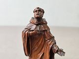 une petite statue représentant un homme vêtu d'une robe et coiffé d'un chapeau