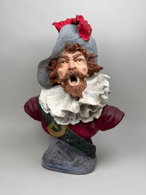 statue of a man with a beard wearing a hat and a red bow