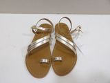 the gold sandals are on a white surface with a price tag