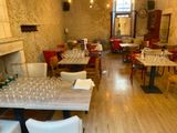 tables and chairs in a restaurant with a fireplace in the middle of the room