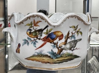 a large bowl with birds painted on it in a glass case