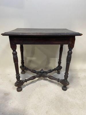une vieille table en bois au plateau noir posée sur un sol blanc