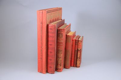 Plusieurs livres rouges sont empilés les uns sur les autres sur une surface blanche