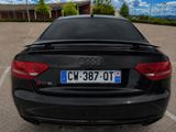 a black car parked in a parking lot with a license plate on the back