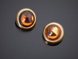 paire de boucles d'oreilles dorées ornées de pierres en verre orange sur fond noir