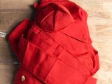 une personne assise à une table, vêtue d'une veste rouge
