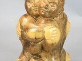 two figurines of two people hugging each other on a white surface