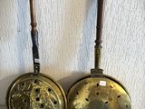 une paire de casseroles et poêles anciennes en laiton accrochées au mur