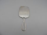 an old silver spatula with a handle on a white surface