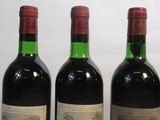 three bottles of red wine are lined up on a table