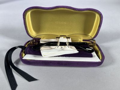 glasses in a purple case on a white surface with a black ribbon