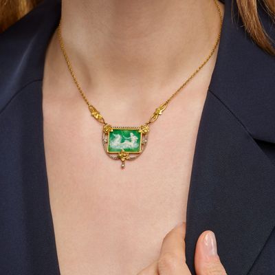 the woman is wearing a necklace with a green stone on it
