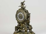 a clock that is sitting on a stand on a white surface