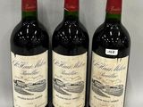 three bottles of red wine are lined up on a white surface