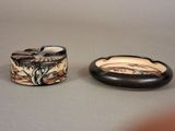 pair of black and white ceramic ashtrays with a painted design