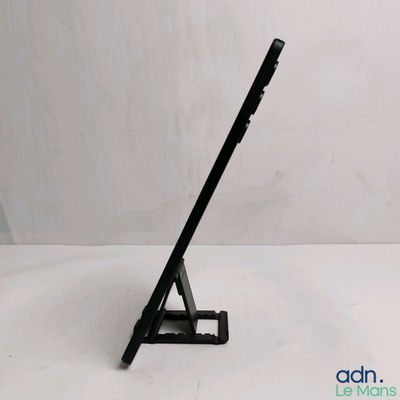 un gros plan d'un ordinateur portable posé sur un support, sur une surface blanche
