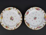 two plates with floral designs on them on a black surface