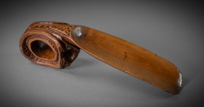 une vieille pipe en bois avec un manche en cuir, posée sur une surface grise