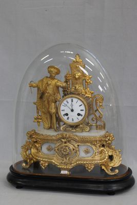 une horloge en or sous un dôme de verre sur une table