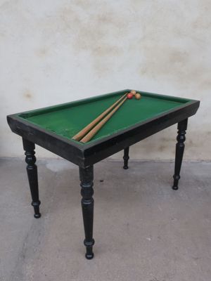 a pool table with two cues on it and a ball on the table