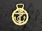 a gold medal with an anchor on it sitting on a black surface