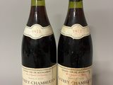 two bottles of red wine sitting next to each other on a table