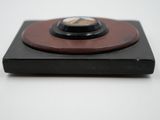 a small clock on top of a black and brown plate