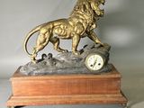 une statue de lion avec une horloge posée sur une table